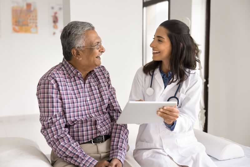 Man with graying hair and glasses speaking with woman doctor. Both are smiling
