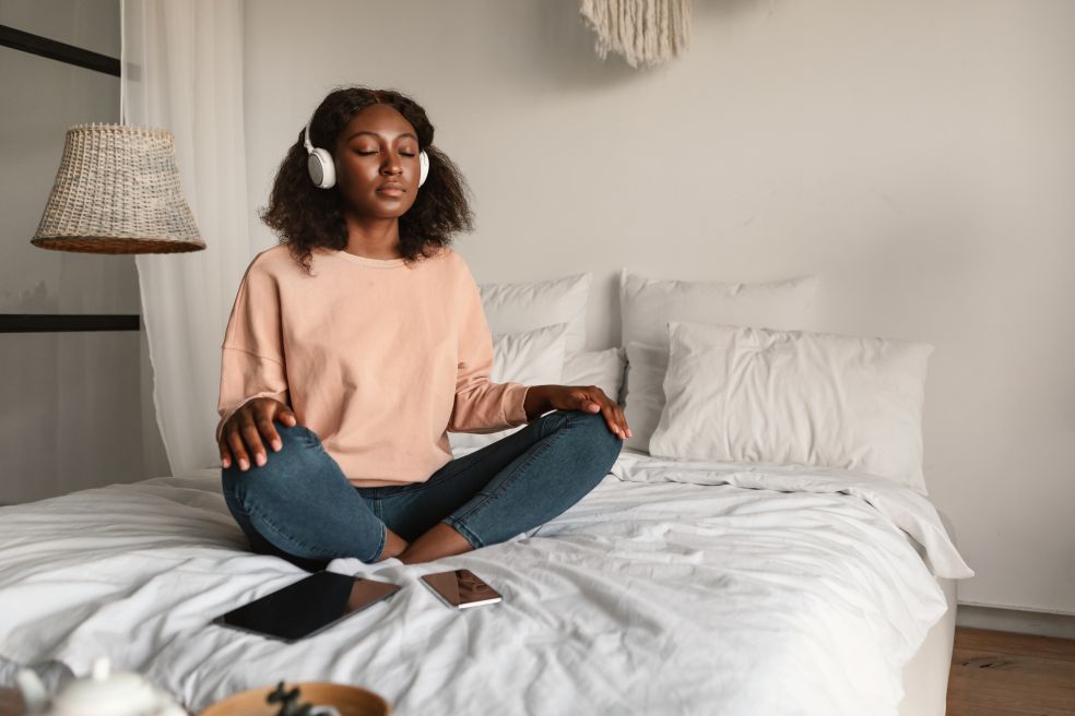 woman sitting on bed with headphones doing mindfulness exercises